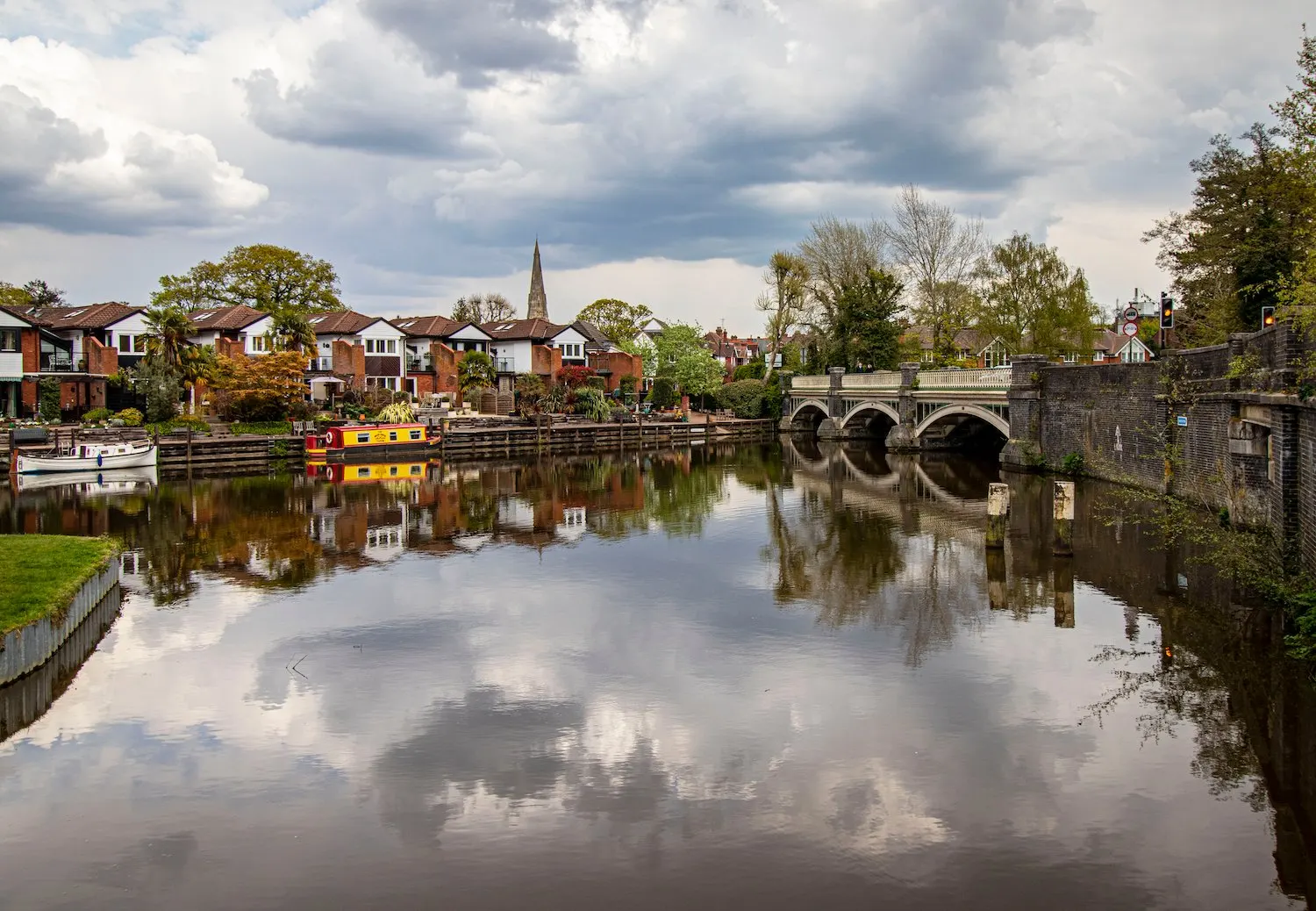 Weybridge river and arched stone bridge, with a church spire reflected in the water